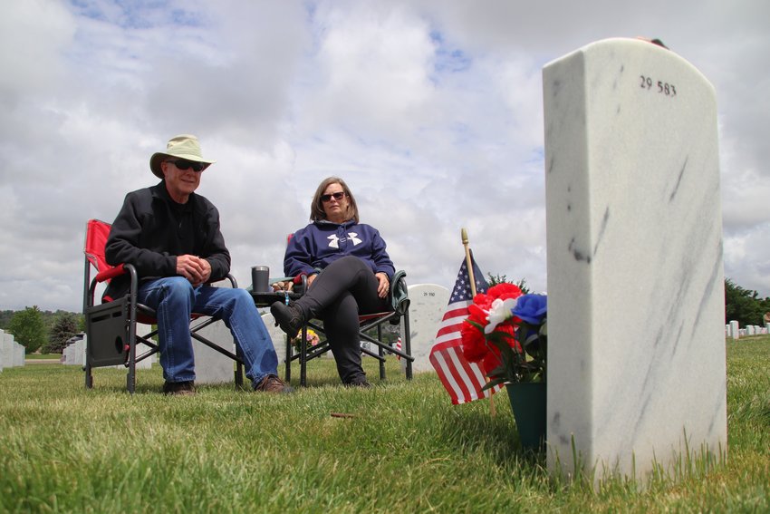 Kirk Newman, left, and Kathie Newman sit before the grave of their son James Hessel, a veteran of Iraq who died by suicide days before his 28th birthday. The Newmans spend every Memorial Day at Fort Logan National Cemetery in southwest Denver.